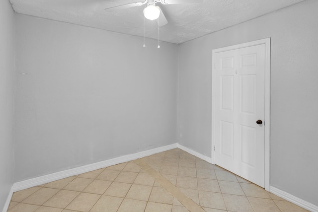 empty room with ceiling fan, light tile patterned flooring, and a textured ceiling