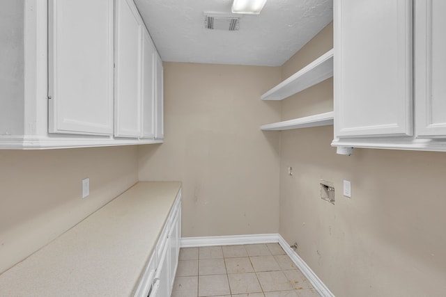 clothes washing area featuring washer hookup, cabinets, and light tile patterned floors