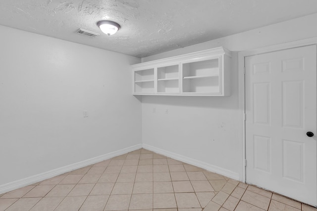 unfurnished room with a textured ceiling and light tile patterned flooring