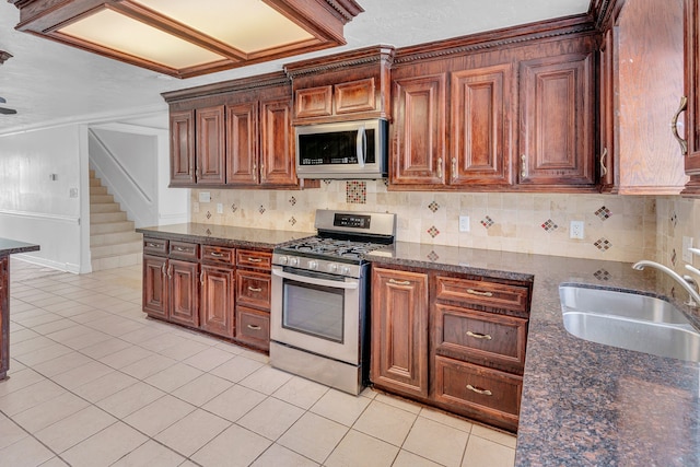 kitchen featuring tasteful backsplash, dark stone counters, stainless steel appliances, sink, and light tile patterned floors