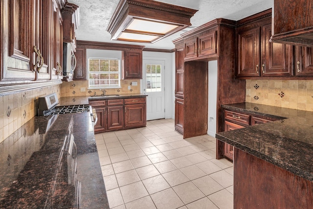 kitchen with dark stone counters, sink, decorative backsplash, light tile patterned flooring, and stainless steel appliances