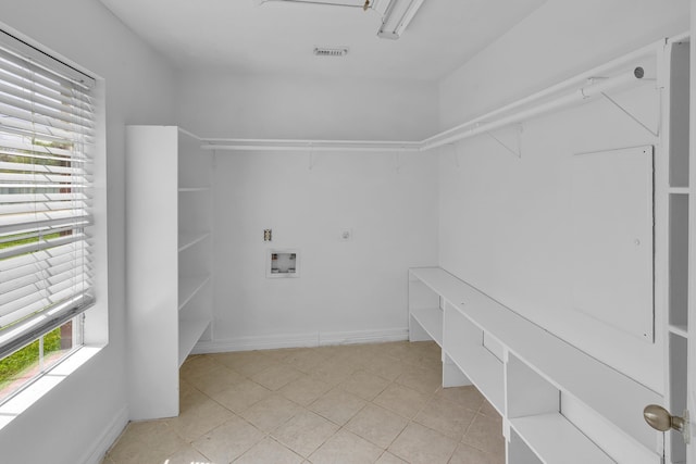 clothes washing area featuring a wealth of natural light, light tile patterned floors, washer hookup, and hookup for an electric dryer