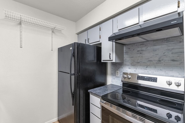 kitchen with tasteful backsplash, black fridge, stainless steel range with electric stovetop, white cabinets, and range hood