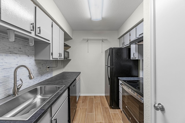 kitchen featuring sink, stainless steel appliances, tasteful backsplash, a textured ceiling, and light wood-type flooring