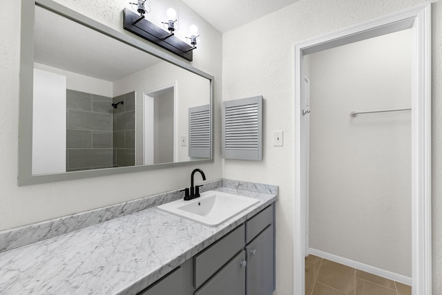 bathroom featuring tile patterned flooring, a textured ceiling, vanity, and a tile shower