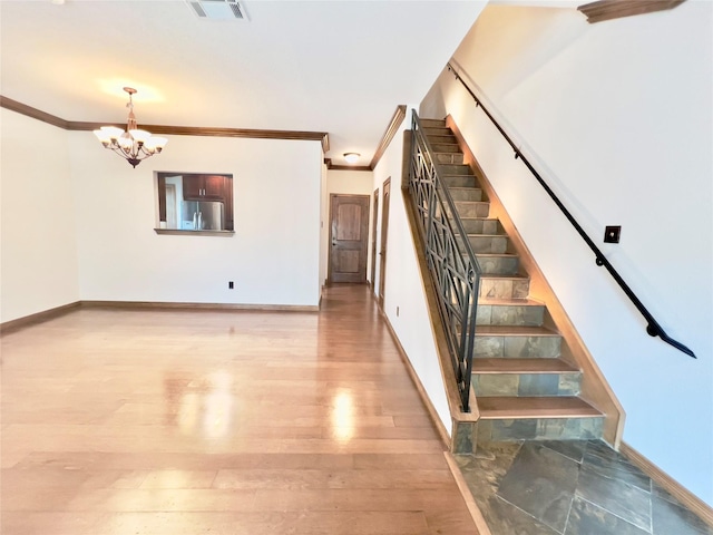 staircase featuring hardwood / wood-style flooring, crown molding, and an inviting chandelier