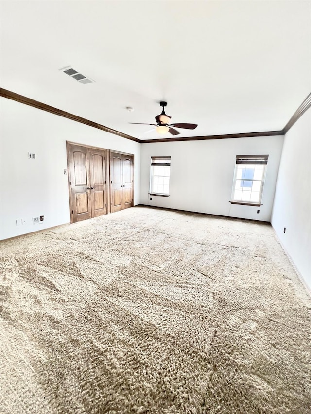 empty room featuring light carpet, ceiling fan, and crown molding