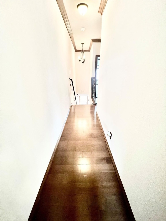 hall with crown molding, dark wood-type flooring, and a notable chandelier