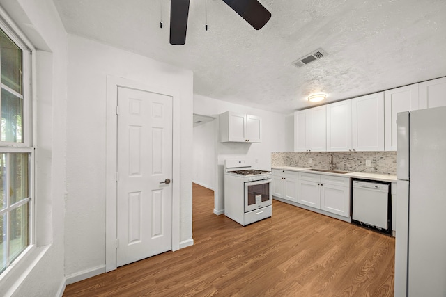 kitchen with white cabinets, white appliances, light hardwood / wood-style flooring, and sink