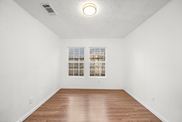 spare room featuring wood-type flooring and a textured ceiling