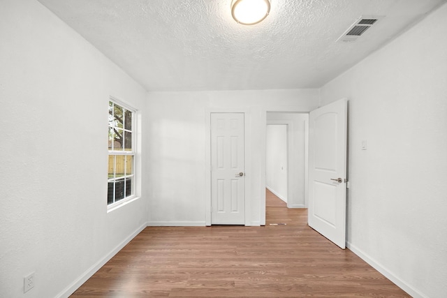 unfurnished room featuring light hardwood / wood-style floors and a textured ceiling