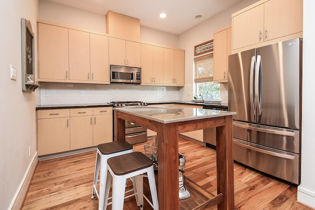 kitchen featuring appliances with stainless steel finishes, backsplash, sink, light hardwood / wood-style flooring, and cream cabinetry