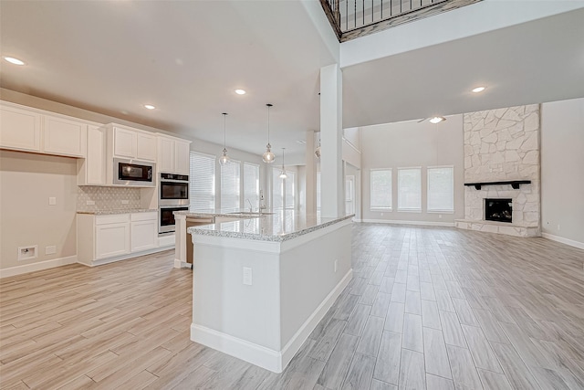 kitchen with pendant lighting, a center island, white cabinets, built in microwave, and double oven