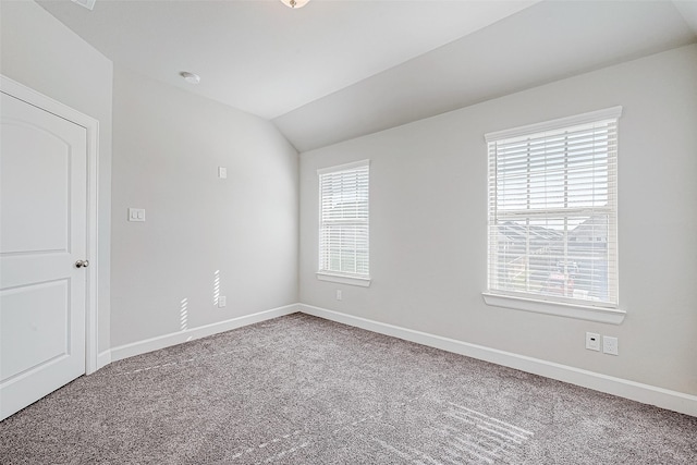 carpeted empty room with vaulted ceiling