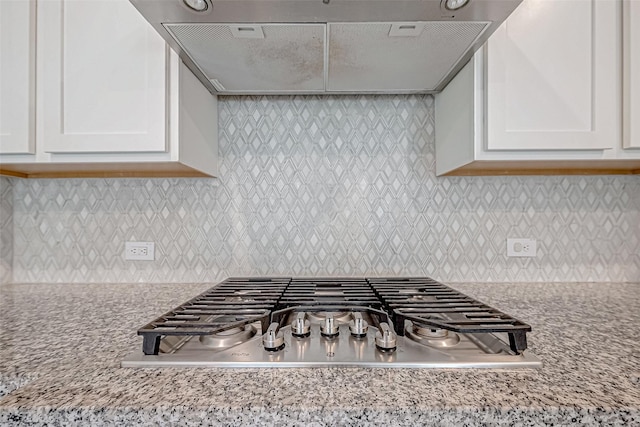 kitchen with backsplash, light stone counters, and range hood