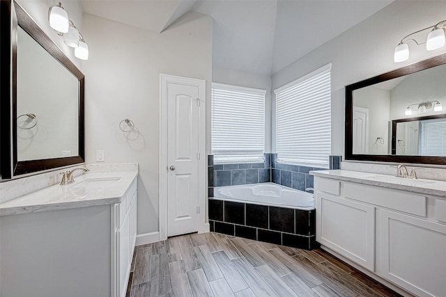 bathroom with tiled bath and vanity