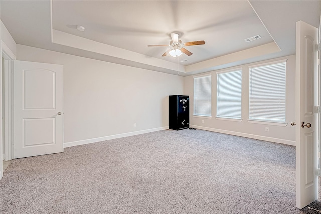 spare room with ceiling fan, light carpet, and a tray ceiling