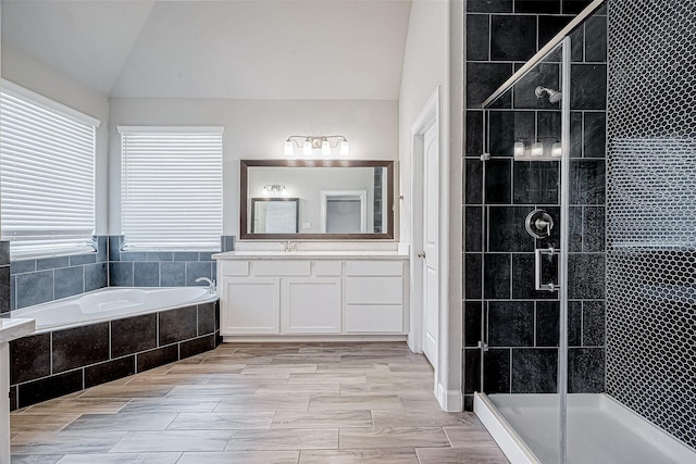 bathroom with vanity, independent shower and bath, and vaulted ceiling