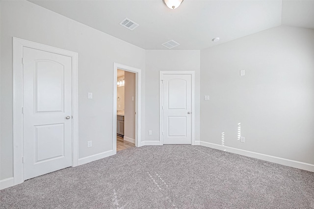 unfurnished bedroom featuring lofted ceiling and light carpet