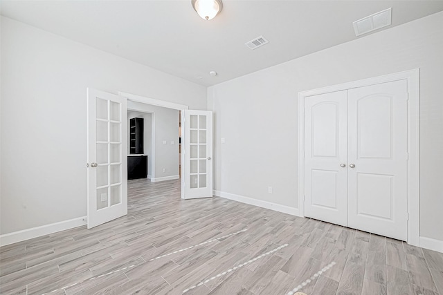 spare room with french doors and light hardwood / wood-style flooring