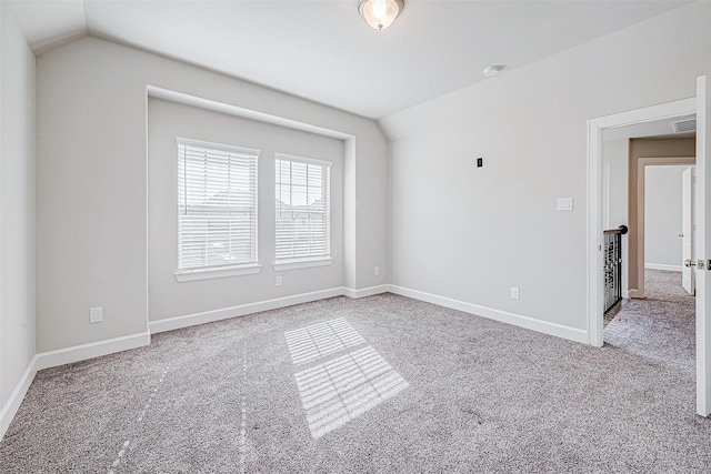 carpeted spare room with vaulted ceiling