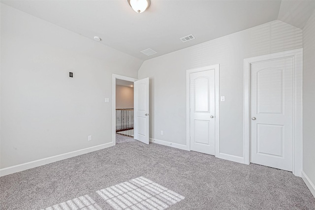 unfurnished bedroom featuring carpet flooring and vaulted ceiling