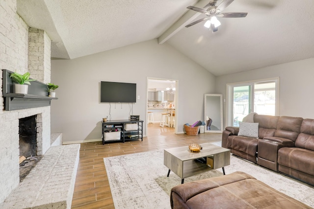 living room with a fireplace, ceiling fan with notable chandelier, lofted ceiling with beams, and a textured ceiling