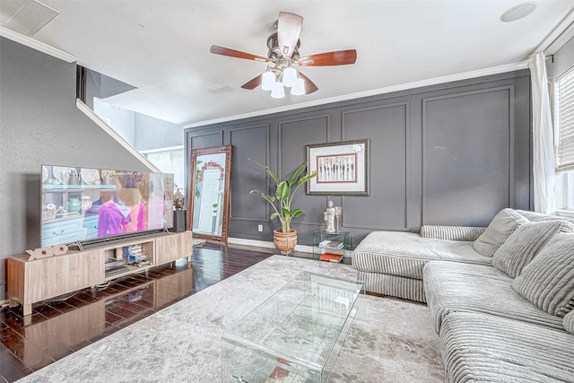 living room featuring dark wood-type flooring, ceiling fan, and ornamental molding