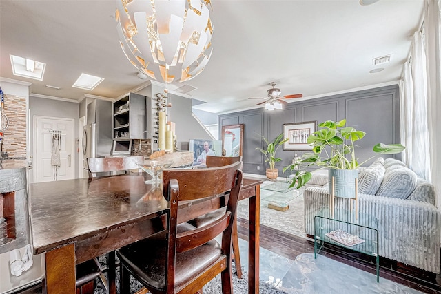 dining room featuring ceiling fan with notable chandelier, a healthy amount of sunlight, ornamental molding, and a skylight