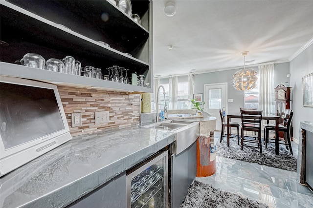 kitchen featuring backsplash, beverage cooler, crown molding, pendant lighting, and a notable chandelier