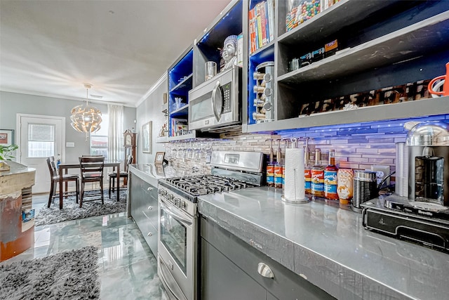 kitchen with ornamental molding, stainless steel appliances, stainless steel counters, a chandelier, and hanging light fixtures