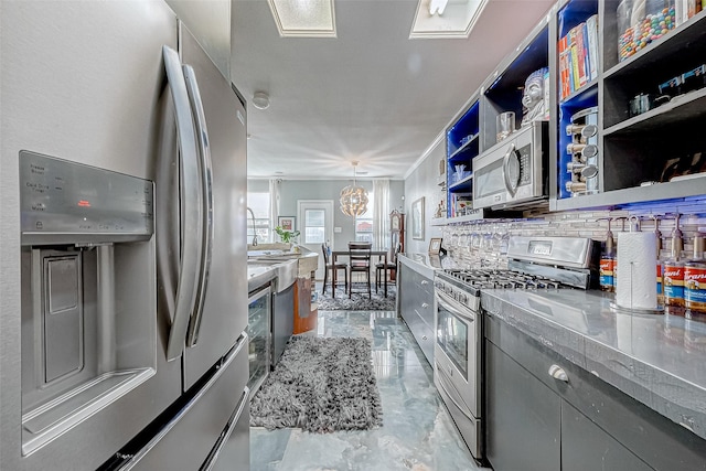 kitchen with decorative backsplash, hanging light fixtures, appliances with stainless steel finishes, and an inviting chandelier