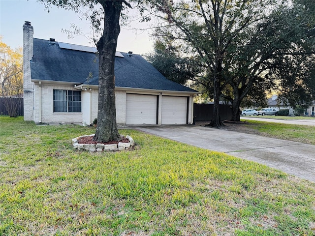 view of side of property with a yard, a garage, and solar panels