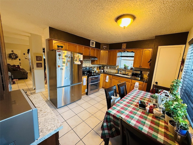 kitchen with sink, stainless steel appliances, backsplash, a textured ceiling, and light tile patterned floors