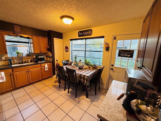 tiled dining area featuring a textured ceiling, plenty of natural light, and sink