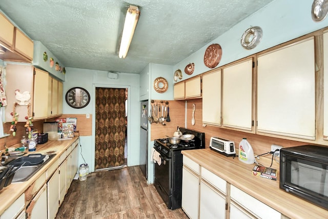 kitchen featuring a textured ceiling, sink, dark hardwood / wood-style floors, and black appliances