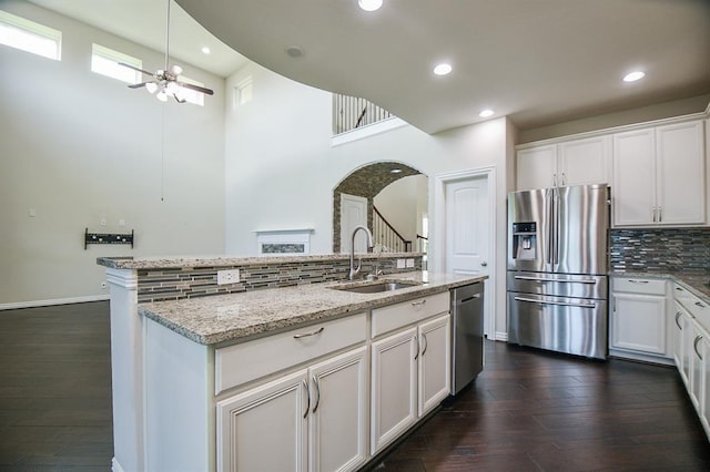 kitchen with dark wood-type flooring, stainless steel appliances, a high ceiling, a kitchen island with sink, and white cabinets