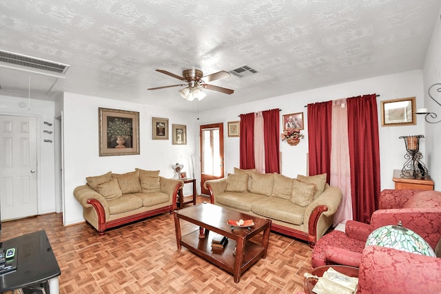 living room featuring a textured ceiling, ceiling fan, and light parquet flooring