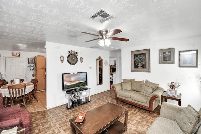 living room with a textured ceiling, light parquet floors, and ceiling fan