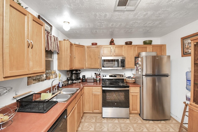 kitchen featuring light brown cabinets, a textured ceiling, stainless steel appliances, and sink