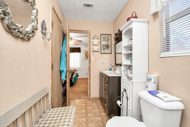 bathroom featuring vanity, a textured ceiling, toilet, and ceiling fan