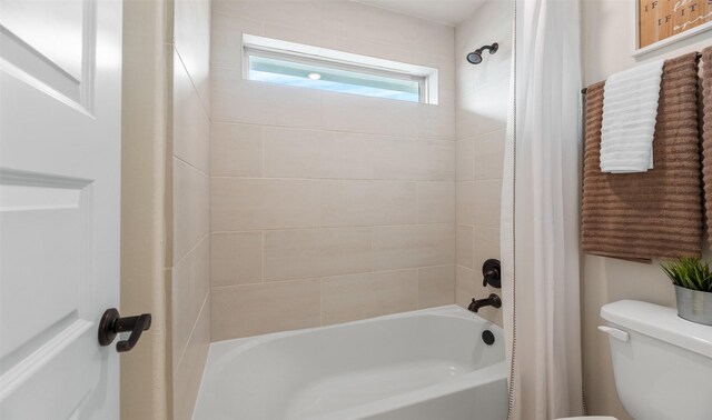 bathroom with tiled shower / bath combo and toilet