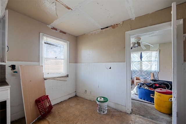 interior space featuring ceiling fan and tile walls