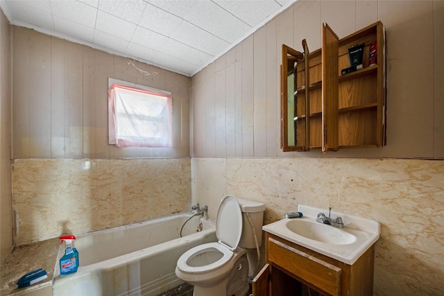 bathroom featuring a washtub, vanity, toilet, and wooden walls