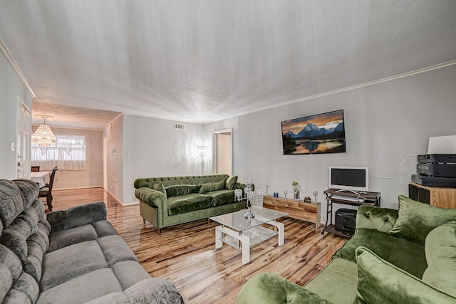 living room with hardwood / wood-style floors, a textured ceiling, an inviting chandelier, and ornamental molding