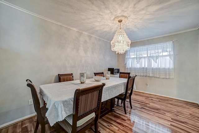 dining area featuring ornamental molding, a notable chandelier, and hardwood / wood-style flooring