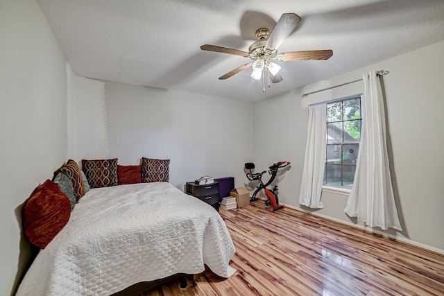 bedroom with ceiling fan, a textured ceiling, and light hardwood / wood-style flooring