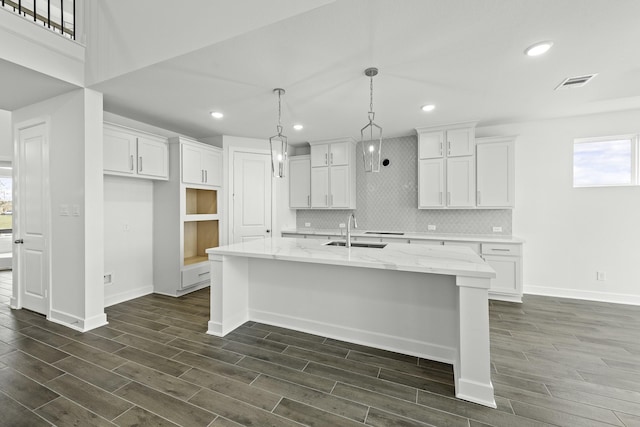 kitchen with white cabinetry, sink, and a kitchen island with sink