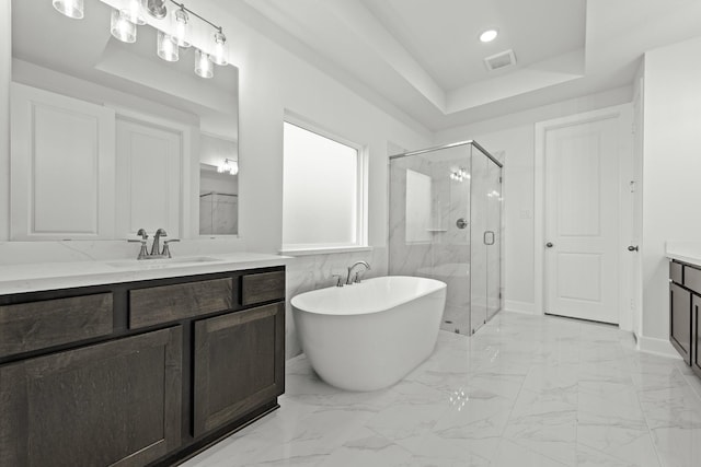 bathroom with a tray ceiling, vanity, and shower with separate bathtub