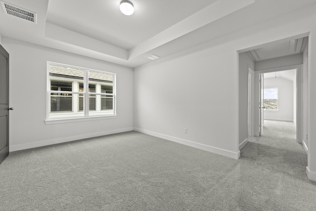 carpeted spare room with a raised ceiling